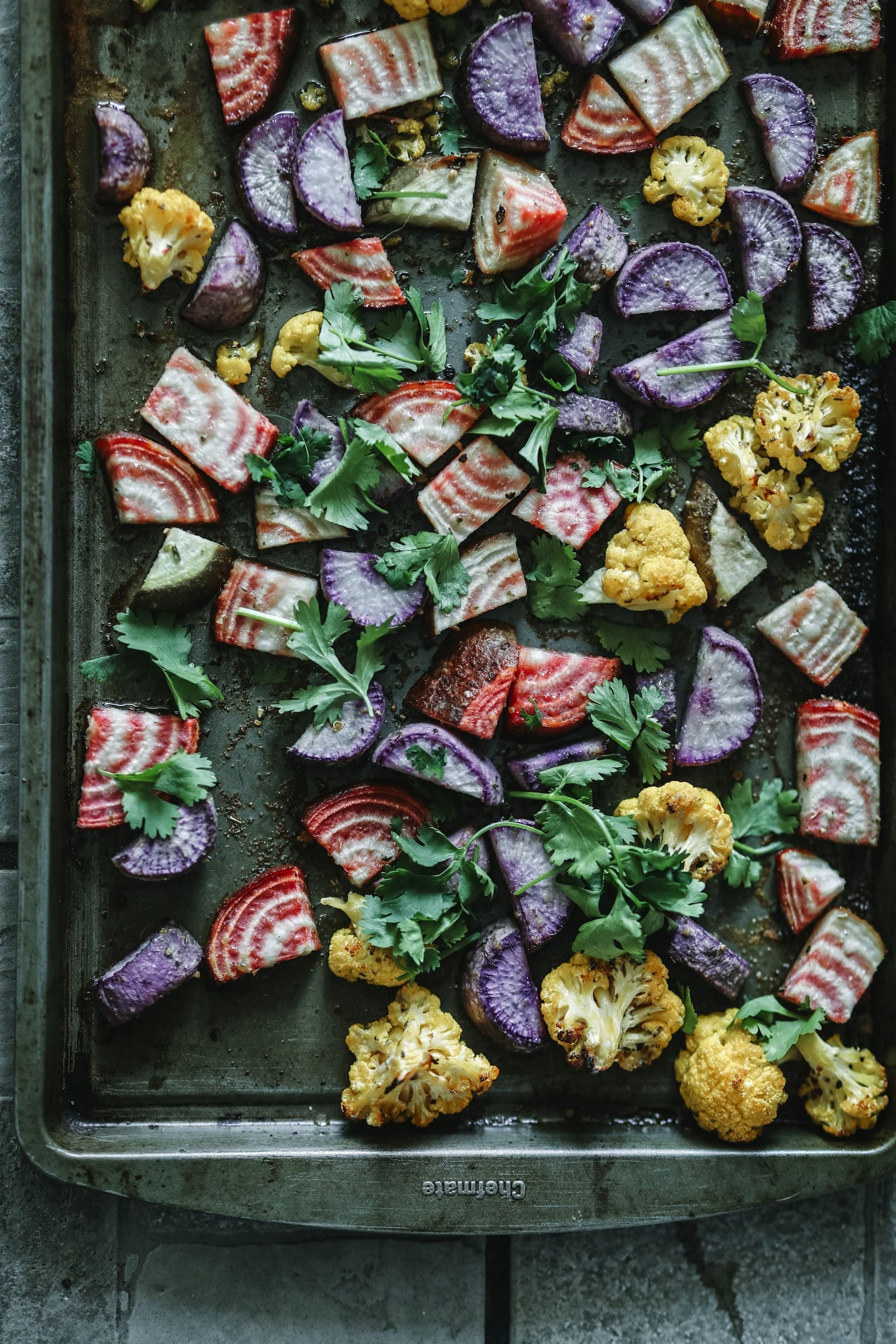 A sheet pan of colorful roasted beets and cauliflower with fresh herbs
